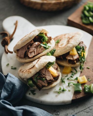 Three pork belly buns on marble serving board