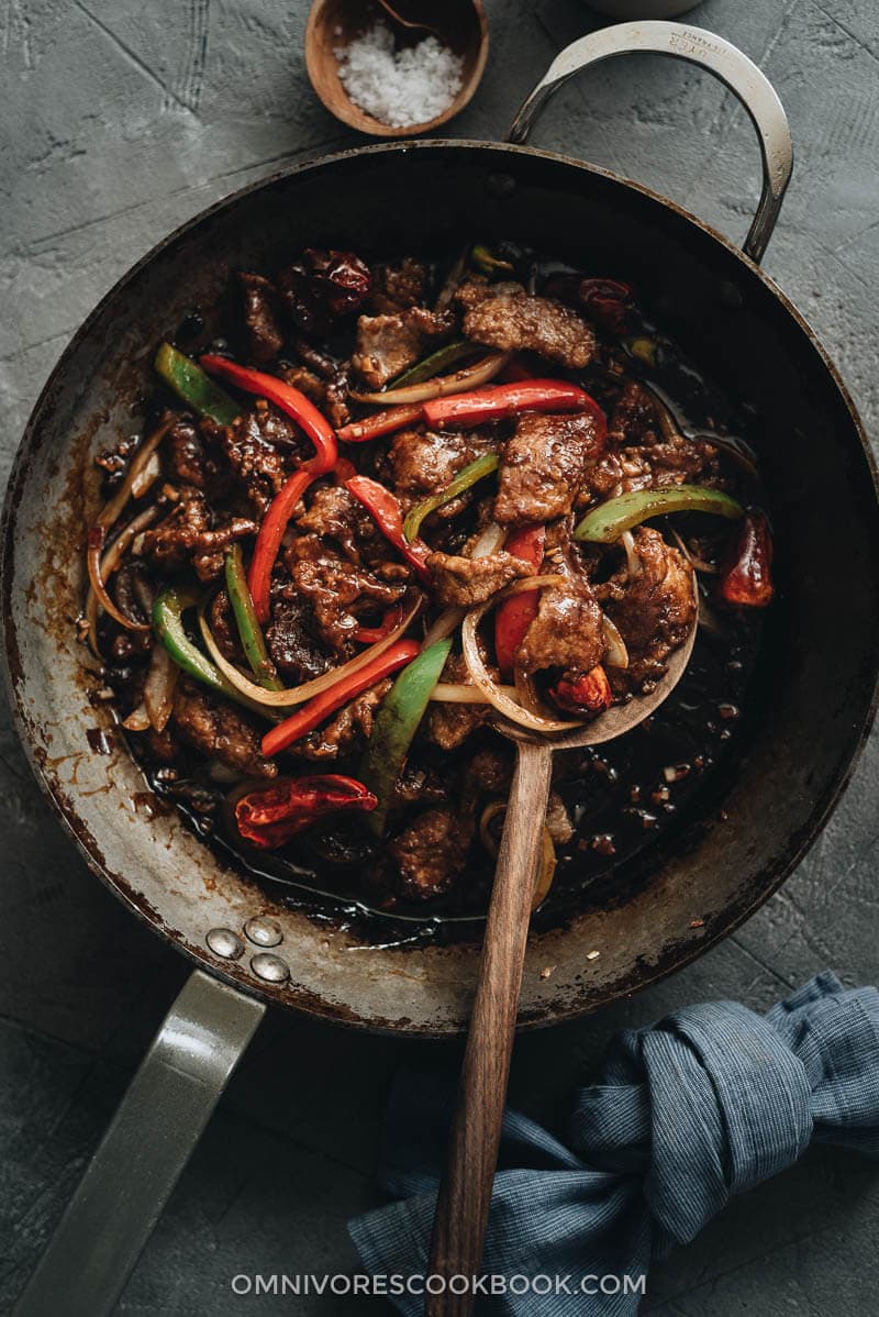 Easy Szechuan Beef Stir Fry - Tender crispy beef cooked in a bold sweet sour spicy sauce with peppers and onions. Learn how to make the richest sauce and create crispy beef without deep-frying. {Gluten-free adaptable} Szechuan beef stir fry in a pan