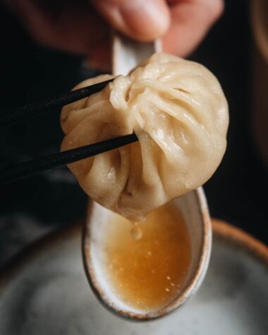 Homemade soup dumplings dripping soup into a spoon