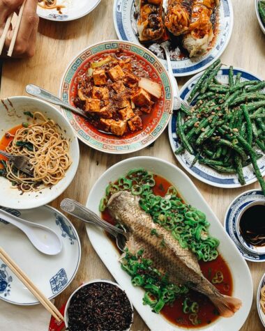 A Sichuan Chinese dinner spread with whole fish, mapo tofu, green beans, and eggplant