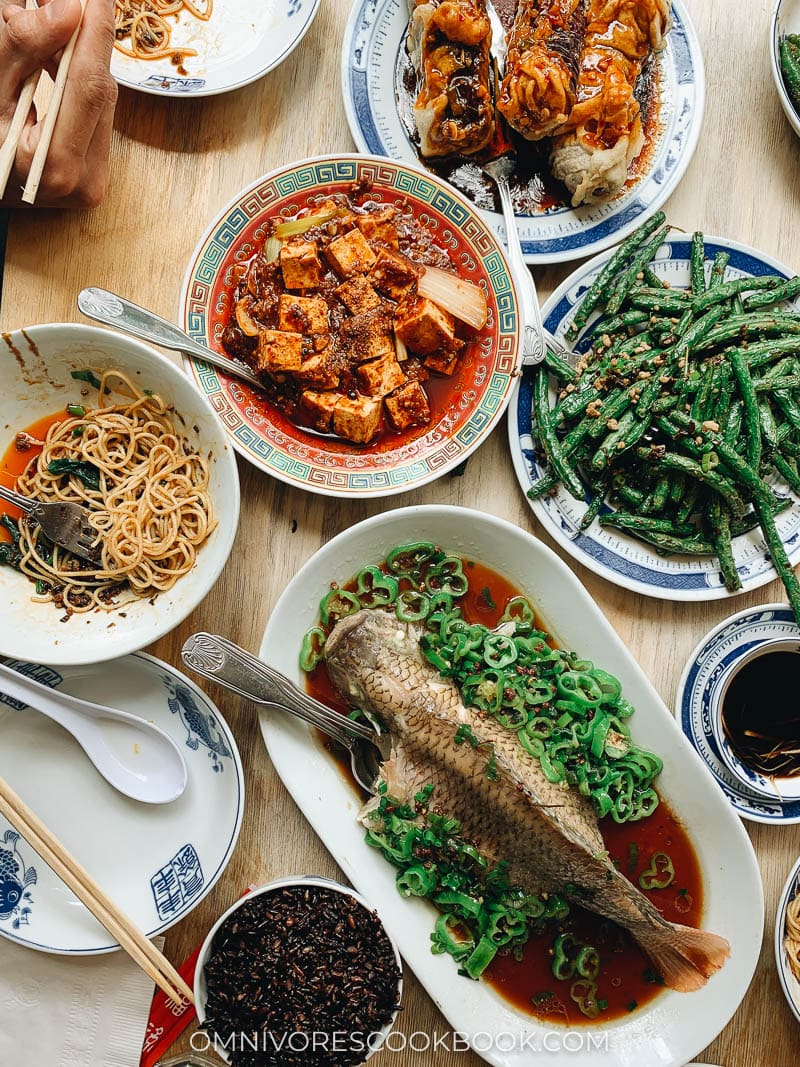 A Sichuan Chinese dinner spread with whole fish, mapo tofu, green beans, and eggplant
