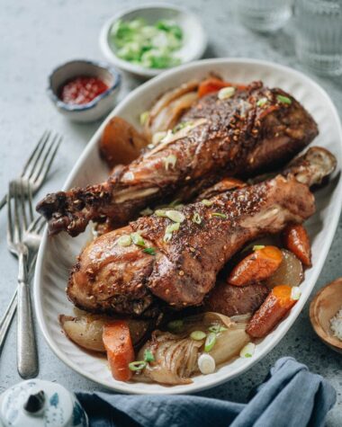 Roast turkey legs over a bed of vegetable served in a platter