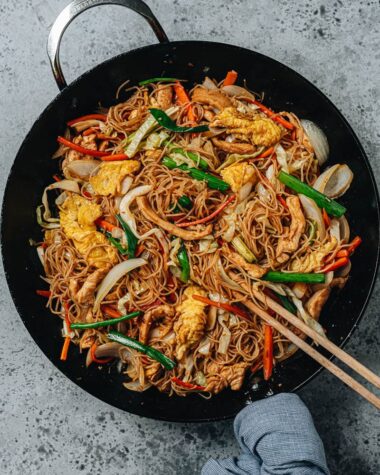 Stir fried rice noodles with chicken, eggs and vegetables in a pan