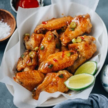 Crispy air fryer wings coated with sauce and served with lime and hot sauce