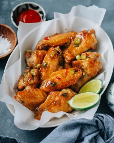 Crispy air fryer wings coated with sauce and served with lime and hot sauce