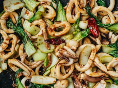 Squid and bok choy stir fry in a pan close up