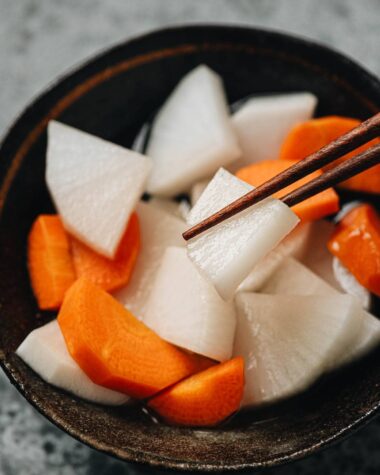 Close up shot of pickled daikon pickled up with a pair of chopsticks