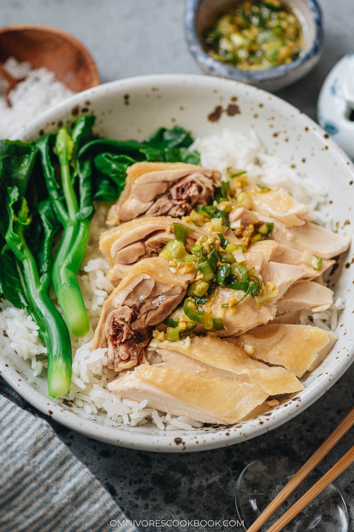 White cut chicken served over rice with gai lan and ginger scallion sauce